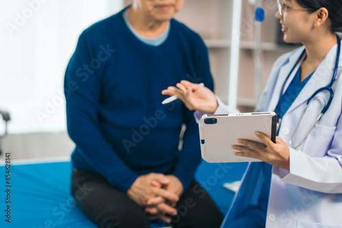 Elderly man engages in thoughtful discussion with compassionate asian people female doctor, addressing health agenda and medical concerns, exemplifying importance of patient-centered care.