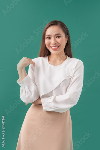 Smiling, beautiful asian woman posing on a green wall.