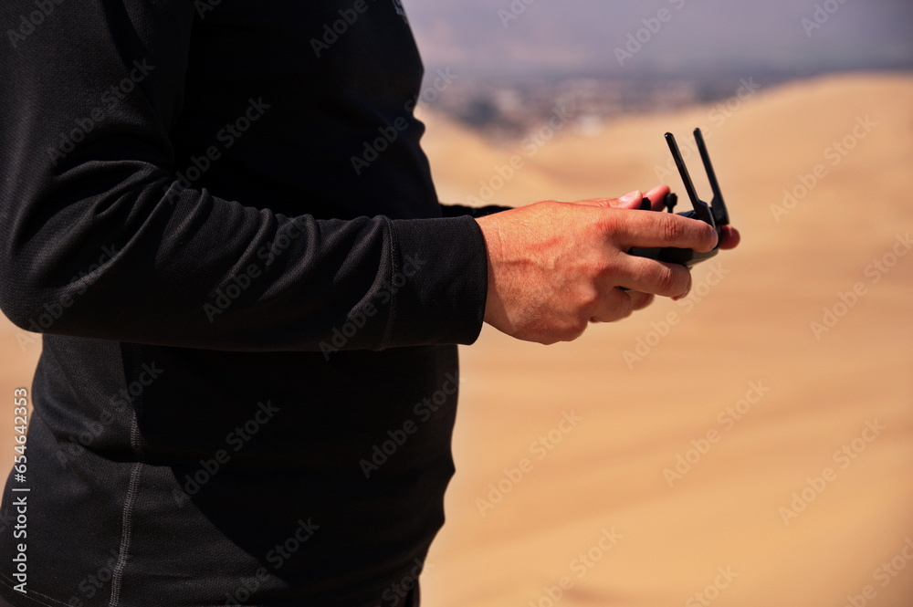 Midsection of mans hands controling drone in desert