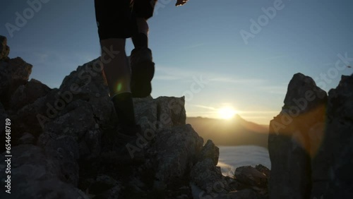 A mountaineer ascends to the top of the mountain step by step with the sun in the background backlit in a beautiful sunrise enjoying the first hours of light of a summer day in the Pyrenees