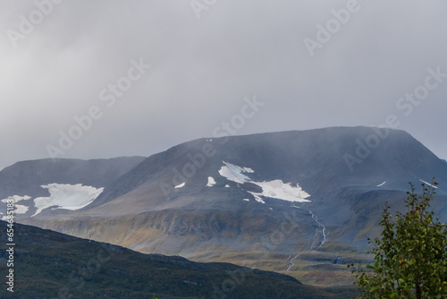 Great mountain view on cloudy weather. Melting snow creating river streaming down to valley. Lyngen Alps.