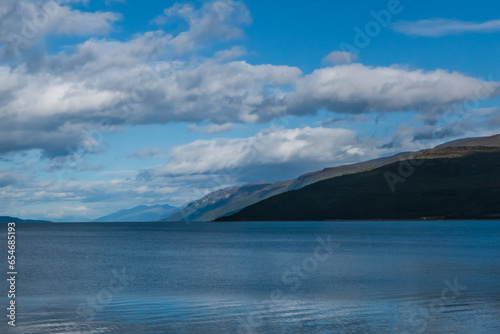 Blue mountain landscape. Sky full of beautiful clouds. Almost calm sea.