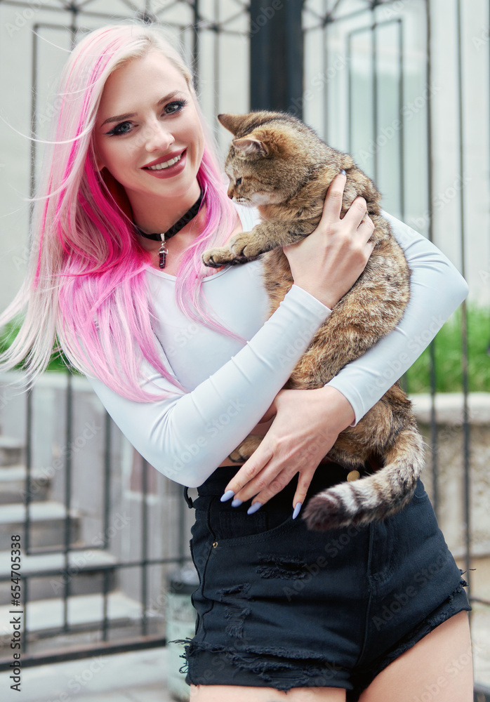 Adorable cute young woman holding sweet cat. Outdoor portrait of smiling lovely girl