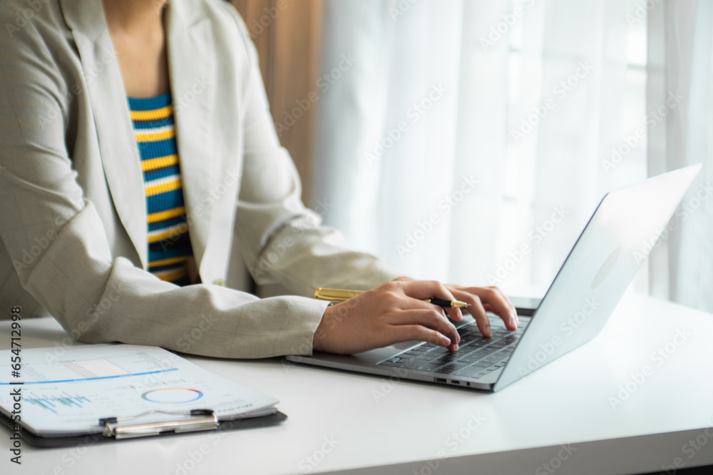 Young Woman Account Manager Working at Table with New Business Project. Typing keyboard,Using Contemporary Laptop. Young Woman Account Manager Working at Table with New Business Project. Typing keyboard,Using Contemporary Laptop.
