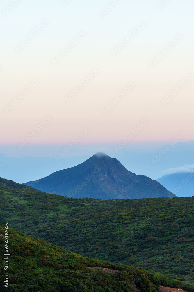 Fototapeta premium 夜明け前の山々の稜線と遠くに霞む山の峰と朝日に照らされて赤くなる空 栃木県那須
