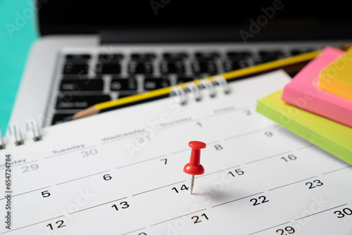 close up pin on calendar with laptop on the table background, planning for business meeting or travel planning concept