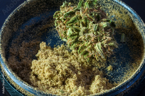 Fotografie herb grinder full of cannabis pollen surrounded by dry flowers of medical mariju