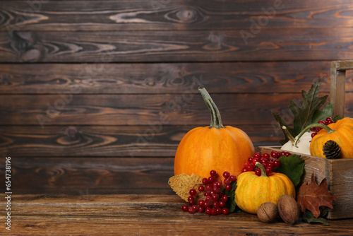 Happy Thanksgiving day. Composition with pumpkins  berries and walnuts on wooden table. Space for text