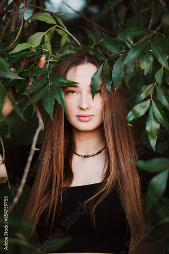 beautiful young woman posing in dark green foliage, girl face on summer nature, beauty and fashion concept