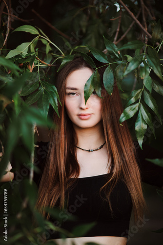beautiful young woman posing in dark green foliage, girl face on summer nature, beauty and fashion concept