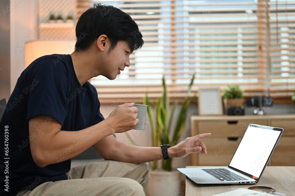 Side view with Young Asian man using laptop at home, Online learning or online meeting concept, Empty screen of laptop. Side view with Young Asian man using laptop at home, Online learning or online meeting concept, Empty screen of laptop.