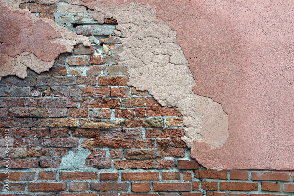 alte, verwitterte Hausmauer aus Backsteinen mit abgebröckeltem Putz