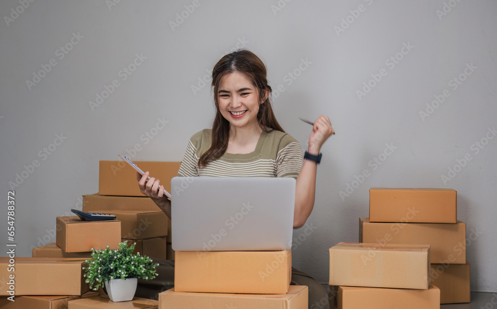 Happy young Asian woman entrepreneur, Smile for sales success after checking order from online Happy young Asian woman entrepreneur, Smile for sales success after checking order from online