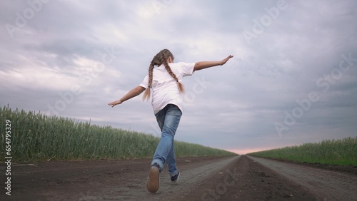 girl child running in nature in the park. happy family kid dream concept. free child daughter runs along a rural road next to a field in nature. free girl runs and plays in the park lifestyle