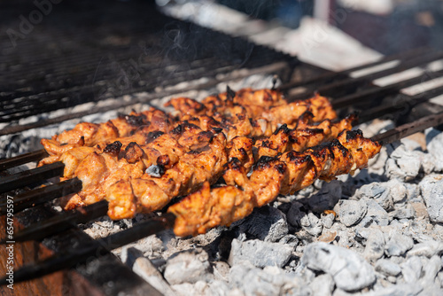 delicious bbq chicken kebab grilling on open grill, outdoor kitchen. food festival in city. tasty food roasting on skewers, food-court. summer picnic photo