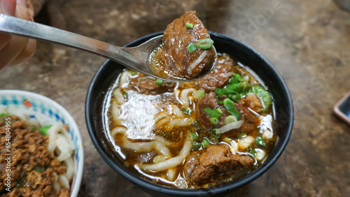 Beef noodles chili sauce served in a bowl on table top view of taiwanese food. Soup beef noodle in a bowl on wooden table. Chinese taiwanese cuisine photo