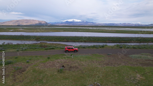 4X4 car driving on a country road in Þjórsardalur valley, along the river Þjorsa, Holtasoley flowers field, nearby the Burfell (Pjorsardal) and Hekla volcano in Iceland. photo