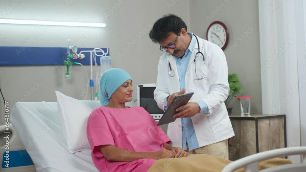 Indian doctor explaining health report from digital tablet to admitted recovered cancer patient at hospital - concept of medicare support, health care guidance and successful treatment. Indian doctor explaining health report from digital tablet to admitted recovered cancer patient at hospital - concept of medicare support, health care guidance and successful treatment.