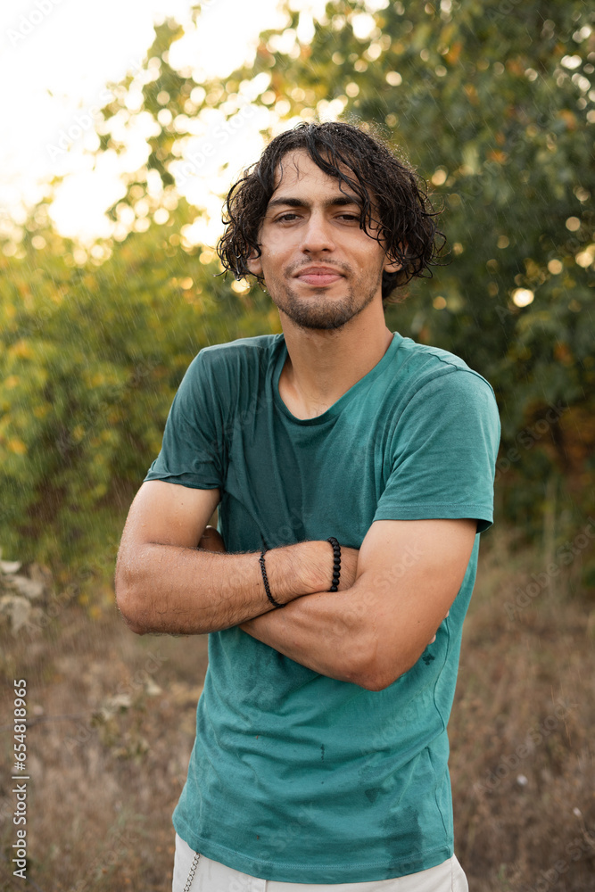Portrait of an Arab guy enjoying the summer rain in the park, a young man in wet clothes looks at the camera smiling friendly Portrait of an Arab guy enjoying the summer rain in the park, a young man in wet clothes looks at the camera smiling friendly