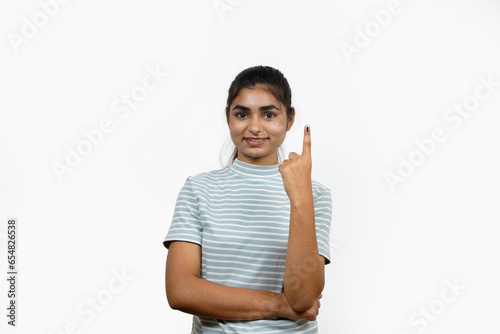 Young Indian girl smiling and pointing after casting her vote, isolated on a white background