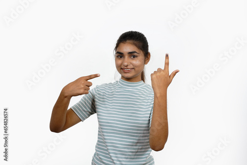 Young Indian girl smiling and pointing after casting her vote, isolated on a white background