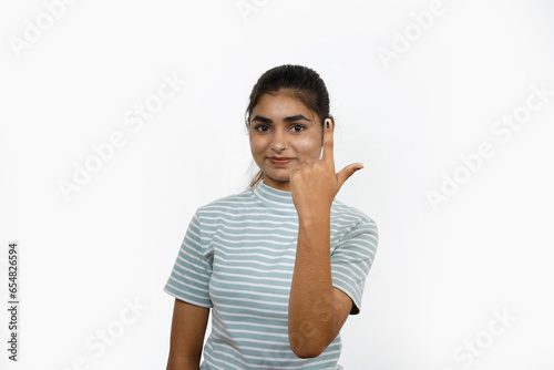 Young Indian girl smiling and pointing after casting her vote, isolated on a white background