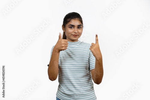Young Indian girl smiling and pointing after casting her vote, isolated on a white background