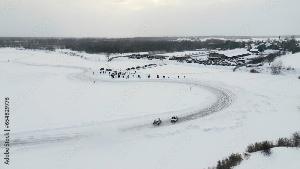 Obraz premium Slow motion of a racing cars championship sliding on an ice track. Clip. Winter drift competitions, aerial view.