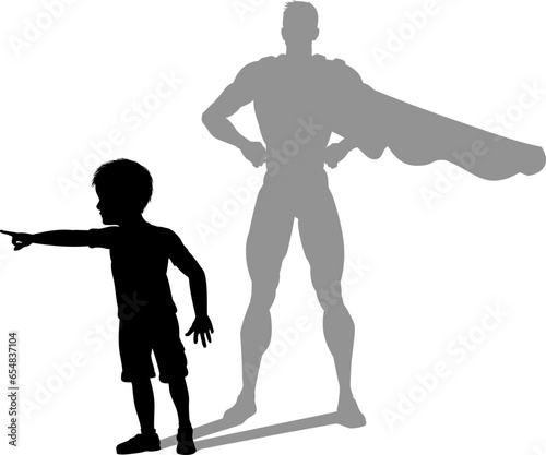 A superhero child or kid boy revealed by his shadow silhouette as a super hero in a cape.