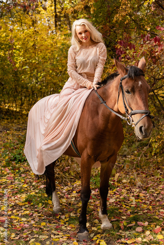 A woman in a long dress sits on a horse. Autumn forest, horse breeding © Ирина Санжаровская