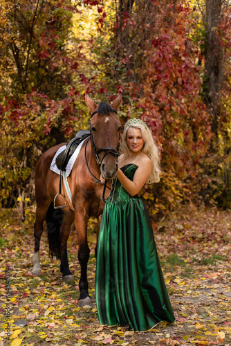 A woman in a long dress stands near a horse in an autumn forest. Riding © Ирина Санжаровская