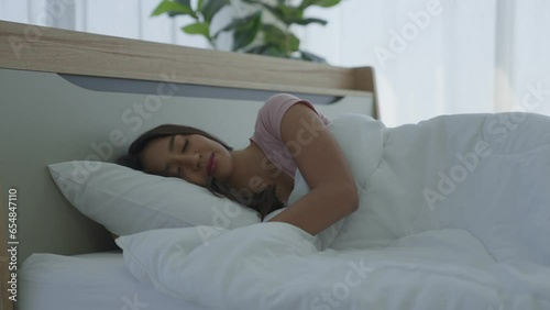 Side View of beautiful asian woman sleep well on bed at night. Panning camera. girl with relax and leisure for health concept.  Girl falling asleep smiling in dark with blue moonlight.