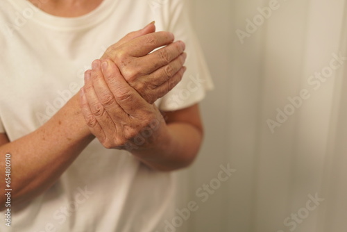 A woman uses her other hand to feel pain and tingling. along with Guillain-Barre syndrome and numbness in the hands Elderly woman tries to massage herself to relieve wrist pain
