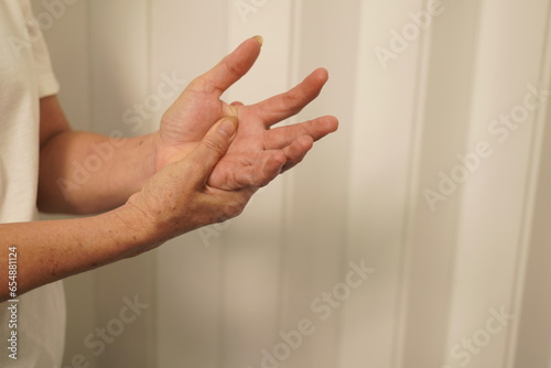 A woman uses her other hand to feel pain and tingling. along with Guillain-Barre syndrome and numbness in the hands Elderly woman tries to massage herself to relieve wrist pain © kiattisak