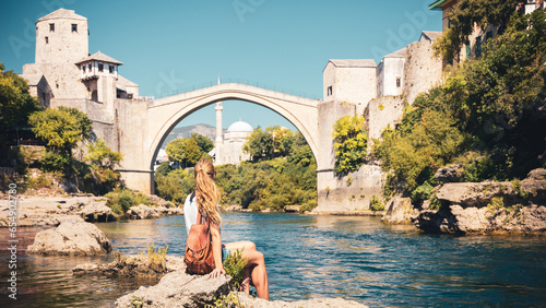 Female tourist looking at famous old bridge and river of Mostar- tour tourism,travel,vacation in Bosnia photo