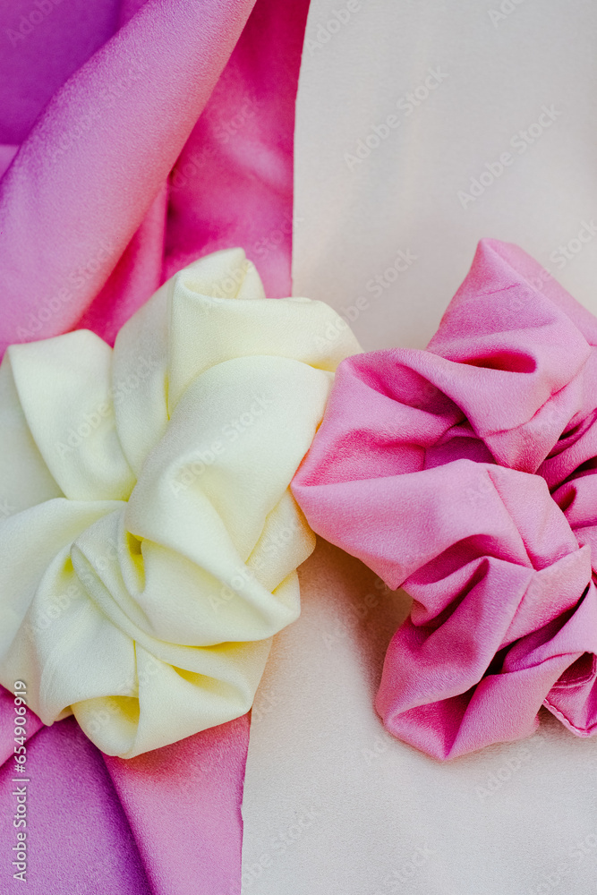 two white, pink scrunchies on soft yellow and pink fabric. Haistyle concept. Hair accessories two white, pink scrunchies on soft yellow and pink fabric. Haistyle concept. Hair accessories