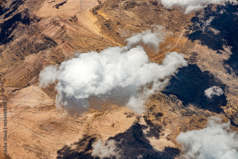 View from 10,000 meters (33,000 feet) of the mountains and arid landscape of western Peru. Dry river paths, dense clouds and no vegetation. - obrazy, fototapety, plakaty 