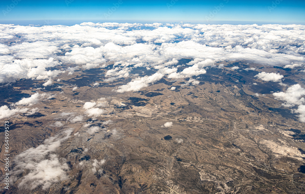 View from 10,000 meters (33,000 feet) of the mountains and arid landscape of western Peru. Dry river paths, dense clouds and no vegetation. - obrazy, fototapety, plakaty 
