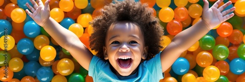 Banner laughing child boy having fun in ball pit on birthday party in kids amusement park and indoor play center, laughing, playing with colorful balls in playground ball pool.