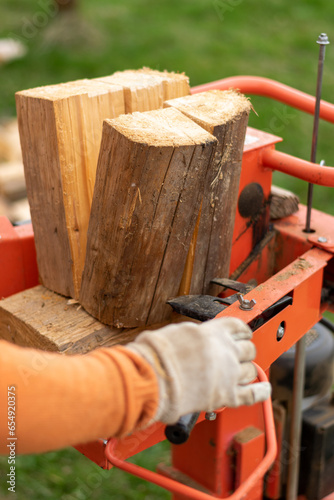 person splitting firewood on a splitter machine, outdoors