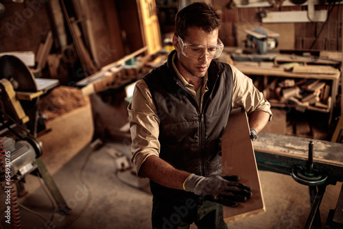 Young male carpenter measuring wood in a carpentry shop