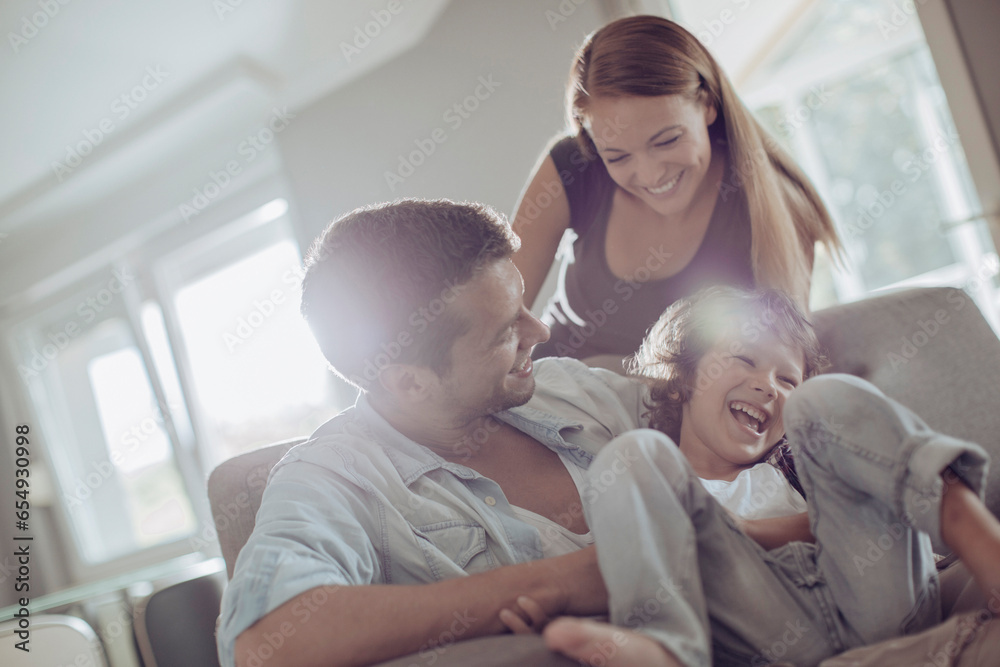 Obraz premium Young family bonding and having fun on the couch at home