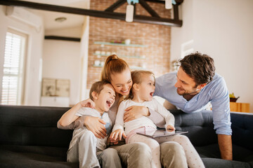 Happy young family bonding and having fun on the couch at home