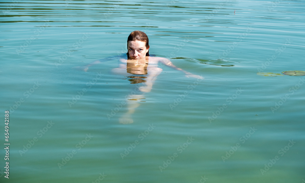young sexy naked woman swimming in blue turquoise green lake water pond