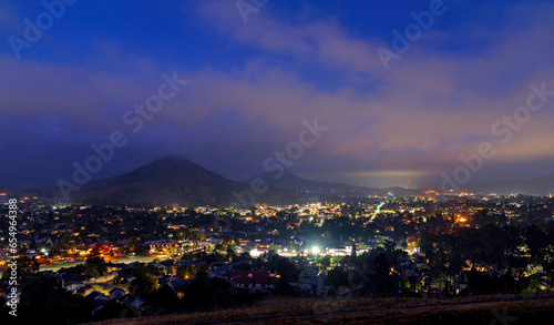 Schilderij op canvas hazy morning with city lights, mountain, sky
