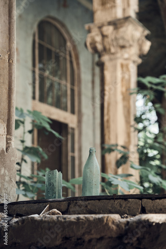 Broken bottles stand on the windowsills. Column with order and vintage window in the background. Abandoned soviet spa resort (sanatorium) Metallurg, in Tskaltubo, Georgia.  photo