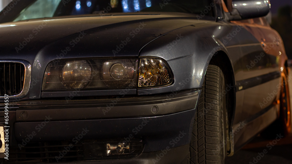 Fototapeta premium Front headlight of an old European car in the evening city