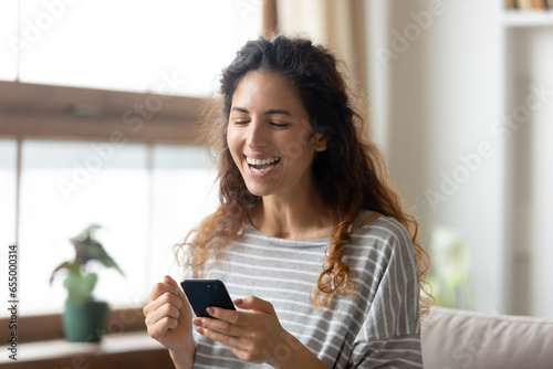 Overjoyed millennial girl hold modern cellphone gadget feel euphoric win online lottery, excited young woman laugh triumph reading good news on smartphone, luck, new technology concept