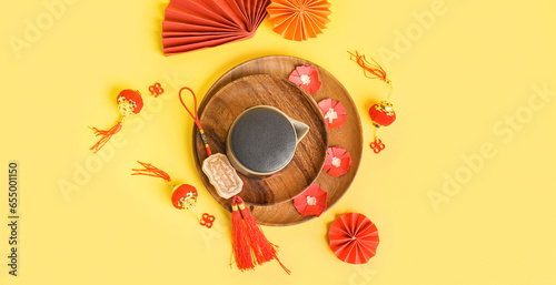 Wooden plates with teapot and Chinese symbols on yellow background, top view photo