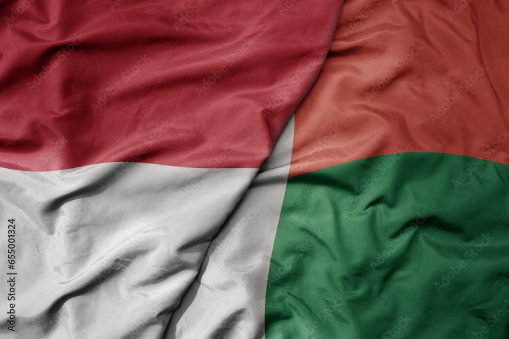 big waving realistic national colorful flag of indonesia and national flag of madagascar .